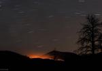 Свечение от пожара и треки звезд на фоне вулкана Закат Солнца